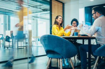 Man and two women sitting in conference room