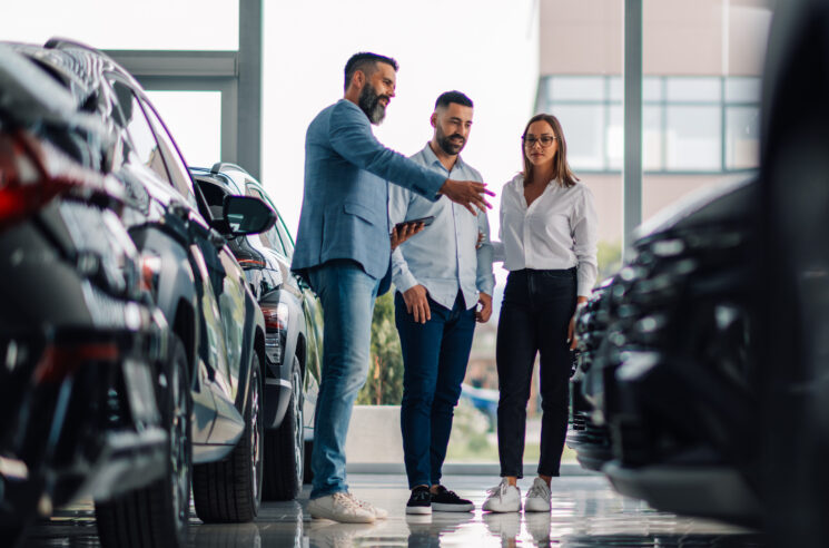 Automotive salesman speaking to customers in showroom