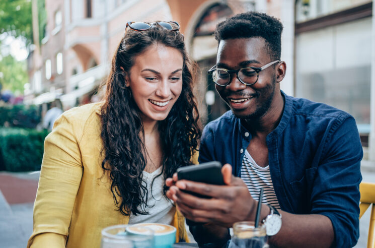 Couple dining outside, looking at phone