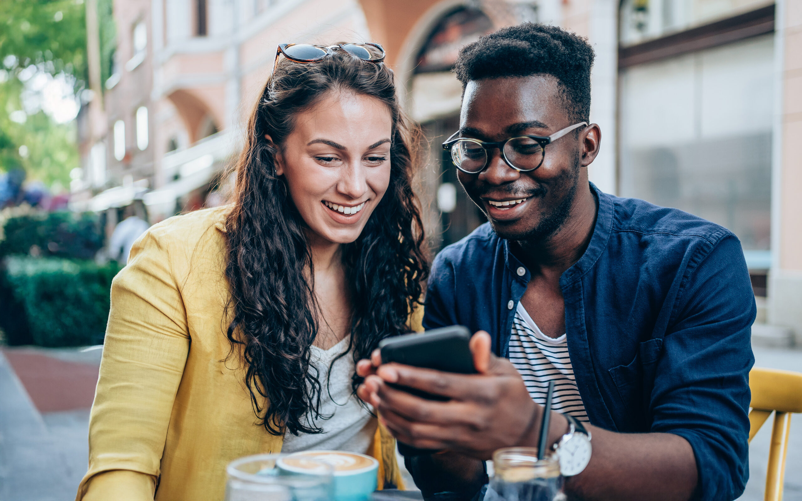 Couple dining outside, looking at phone