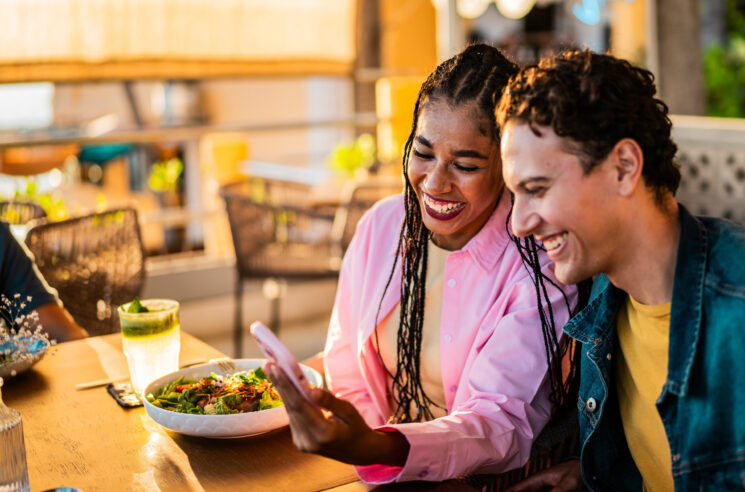 Happy woman and man leaving review on phone in a restaurant