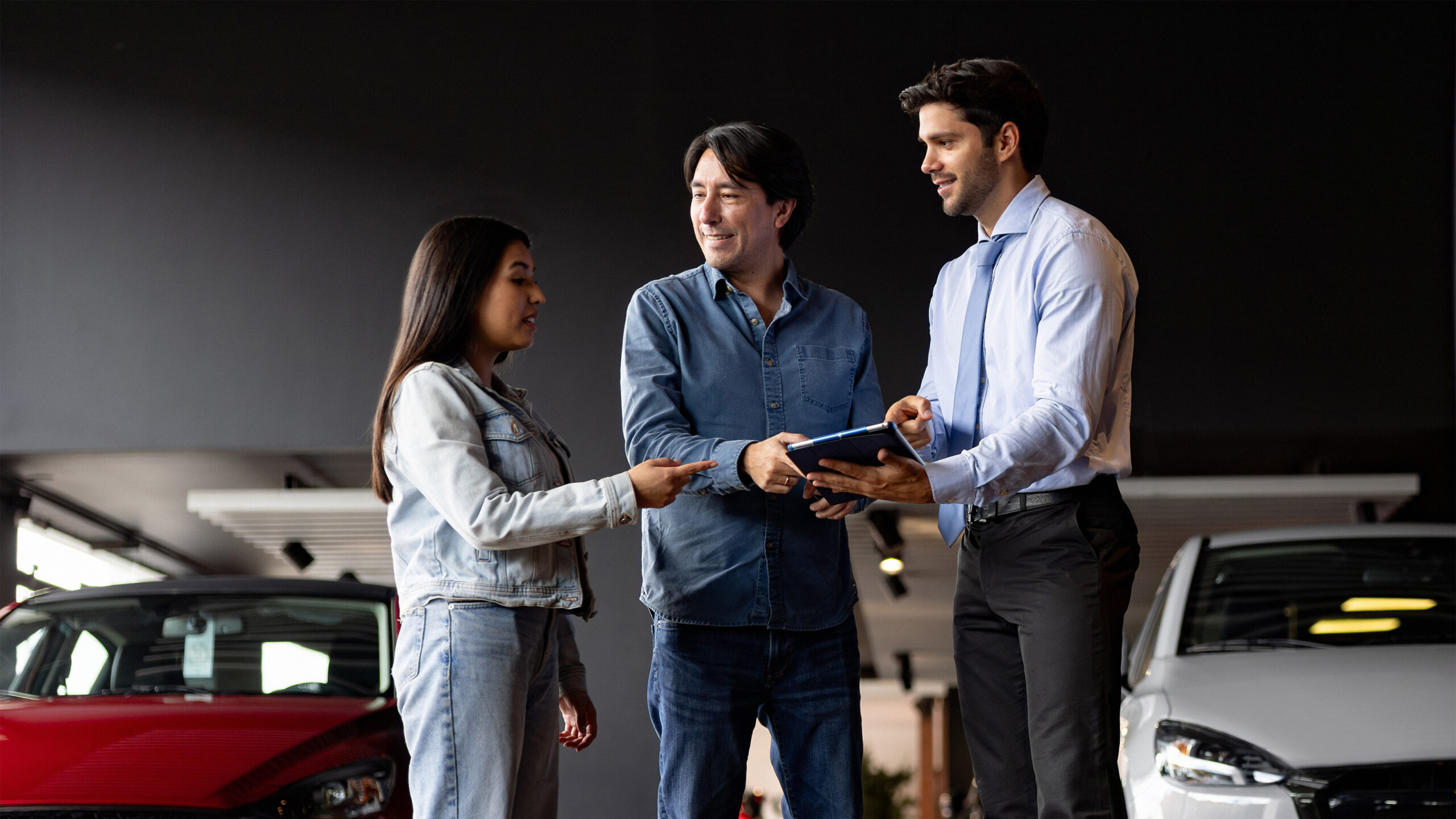 Customers working with auto salesman in showroom.